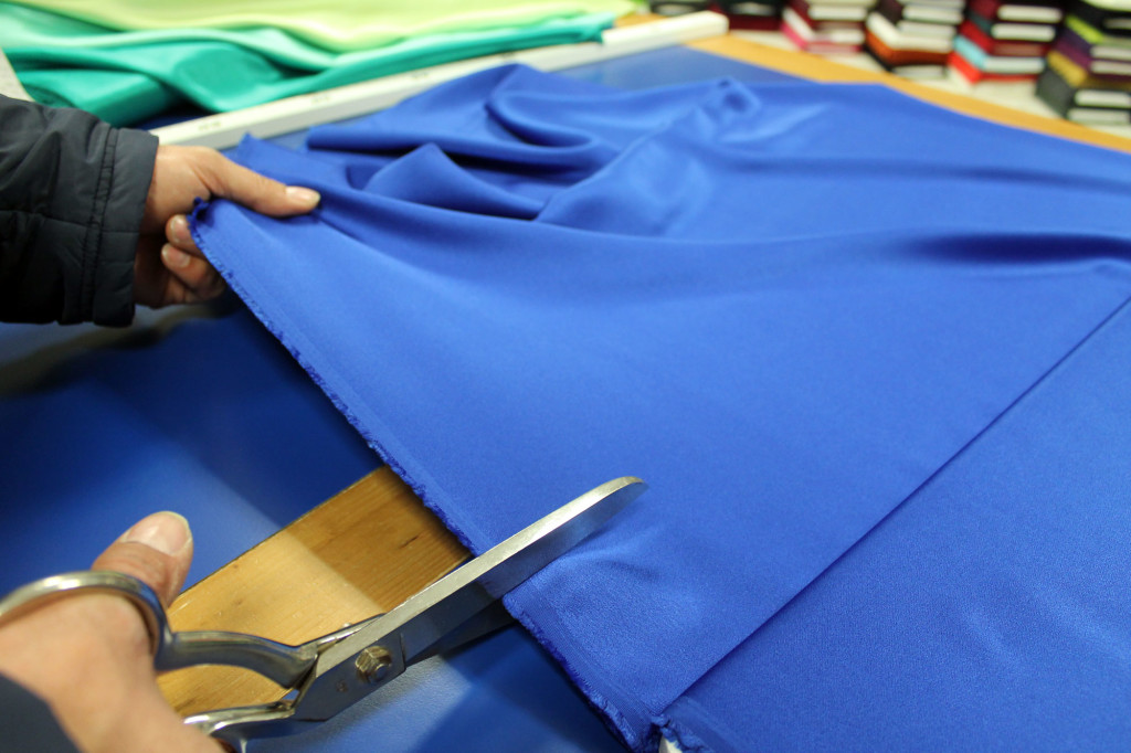 Tagliando un tessuto blu sul tavolo da lavoro dell'Arcobaleno.